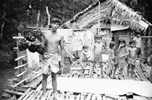 00671 Prints: A Borneo headhunter tribesman seen here holding up a basket of human skulls