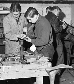 A boy is shown how to replace the heel of a boot. He is at work