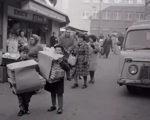 Two boys carrying boxes of Christmas crackers to help the festive season go off with a