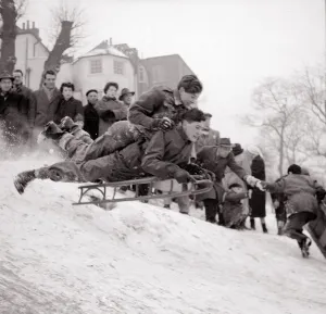 Boys goes flying down a snow covered hill on a sledge at Hampstead Heath February