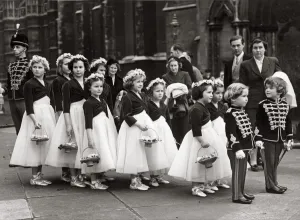 Weddings Prints: Two boys tressed as toy soldiers marshalling a long line of bridesmaids outside St
