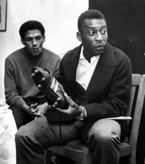 Brazilian football star Pele looking at a pair of football boots as team mate Garrincha
