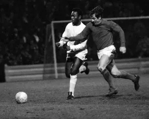 Brazilian football star Pele of Santos chases for the ball with Alan Mullery of Fulham