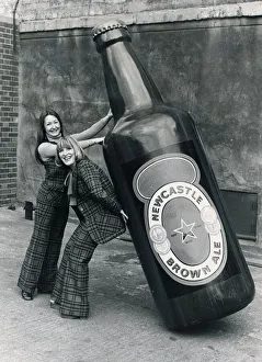 Brenda Kelly (without jacket) and Jennifer Donkin holding a nine foot tall bottle of