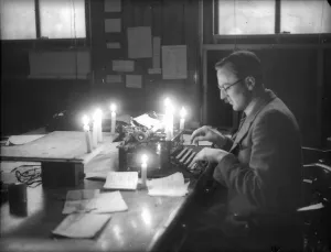 Journalism Prints: Bristol a newspaper reporter works by candlelight in January 1941 after bombs cut off