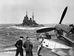 A British battleship at sea seen from the flight deck of the aircraft carrier HMS