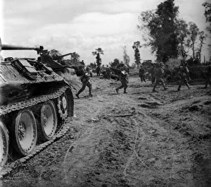 British infantry passing a knocked out German tank as they move up to consolidate a