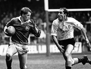 British Lions Prints: British Lions v Rest of The World. Ringland about to hand off the flying Frenchman Esteve