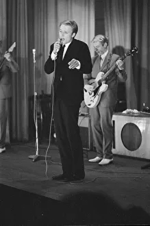 British pop singer Mike Sarne performing on stage with his band