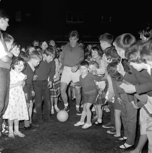 British rocker Tommy Steele playing football with children of the Tachbrook Estate in