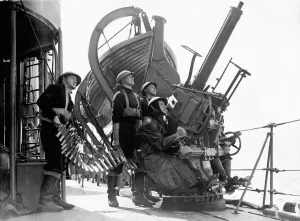 British Royal Navy sailors aboard a destroyer on escort duty fire warning shots to an