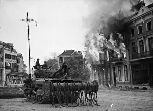 Holland Prints: A British Sherman Crab flail tank moves up through the burning buildings in Arnhem