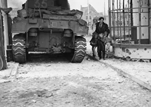 A British Sherman tank pauses for a moment as a Dutch civilian lifts his two children