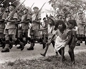 South America Prints: British soldiers marching in Georgetown British Guiana followed by some children in 1953