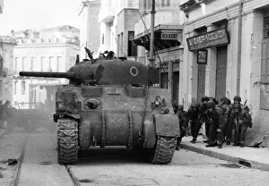 Greece Prints: A British tank gives covering fire to a street patrol in Athens. 1944