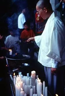Images Dated 1st January 1997: Buddhist monk lighting candles at a Buddhist church service circa 1997