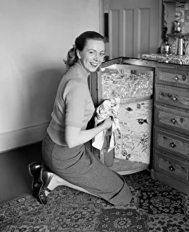 A busy housewife polishing the furniture at home Circa 1954