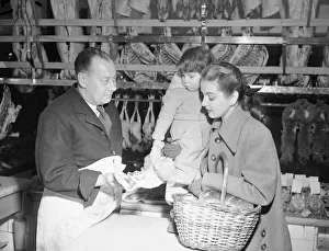 Basket Prints: Butcher offers choice cuts of meat to a woman shopper March 1952