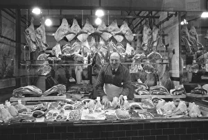 Butchers Prints: Butcher standing in his shop window, showing off his various meat products currently