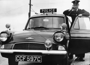 Motors Prints: A Cambridgeshire police officer driving a Ford Anglia police car at Mildenhall