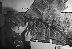 Photograph Prints: A Canadian Photographic Reconnaissance pilot examines a picture of Hamburg