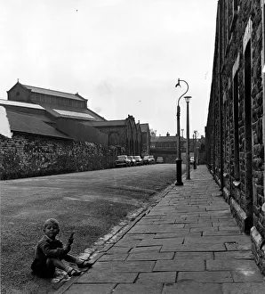 Core77 Prints: Cardiff - Old - Adamsdown - A young child sits in the gutter in Cycle Street with