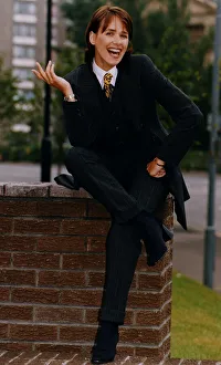 Carol Smillie TV Presenter in three piece suit sitting on wall A©mirrorpix