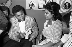 Cassius Clay aka (Muhammad Ali) signs his autograph on a slipper for a fan in London