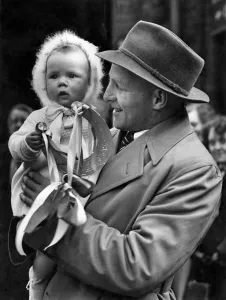 Ces Mountfords baby daughter Carolyn gives her daddy an emblem of Good Luck before
