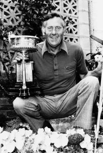 Charlie Green kneeling in garden holding lawn trimmers in one hand