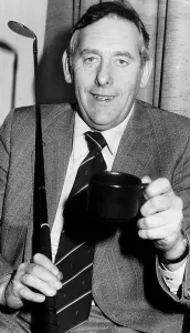 00189 Prints: Charlie Green sitting holding up mug with golf club resting on shoulder