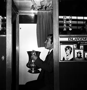 Chelsea captain Ron Harris sits in the Photo booth on Piccadilly station with the FA Cup