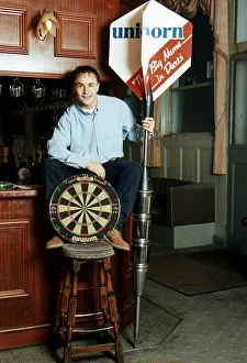 Chelsea and England footballer Dennis Wise poses in a public house with a dartboard