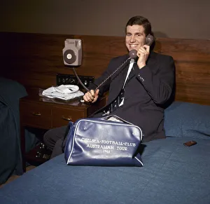 00208 Prints: Chelsea footballer Peter Osgood on the telephone in his hotel room packing his bag