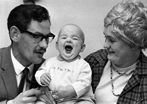00077 Prints: Children - Babies. Chuckles from miracle baby Shaun as he sits with his mother and father