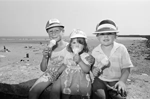 Children enjoy an ice cream as they try to keep cool on Coney Beach in Porthcawl
