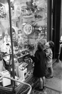 Children look longingly at toys into shop window at Christmas, 16th December 1960