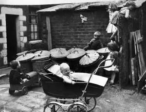 Children play amongst the rubbish bins in the back yard of their houses as a little baby