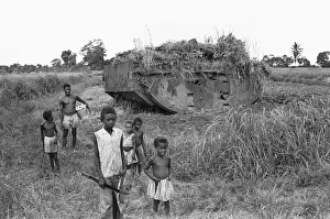 00671 Prints: Children playing near a weed strewn Buffalo LVT American tank in a potato field