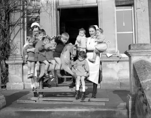Nursery Prints: Children playing on a rocking horse at a day nursery in London circa 1945