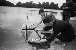 Children sailing their toy yachts on the Round Pond in Kensington Gardens, London
