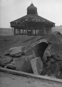 Children search a crater for shrapnel following near miss to a public shelter in Aston