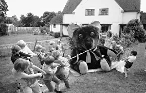 Strength Prints: Children from the village of Longarish pull along a giant teddy bear on a trolley through