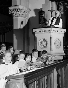 00109 Prints: Choirboys reading their books in church during a priests sermon Circa 1954