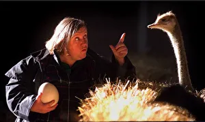 Clarissa Dickson-Wright with one of her osriches holding egg pointing finger