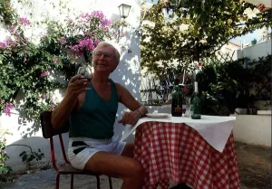 Clive Dunn actor sitting at table outside house drinking wine November 1989