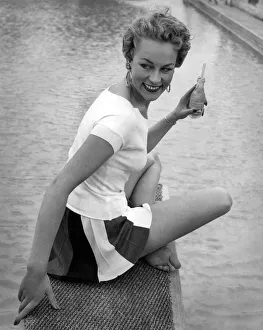 Clothing Beach. Model sits by the water with a drink wearing white t-shirt