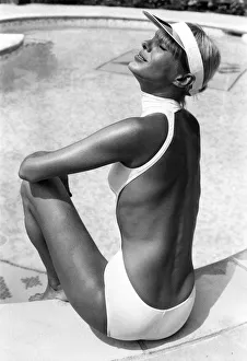 Clothing Beach. Tanned woman models sun visor and white one piece halterneck backless