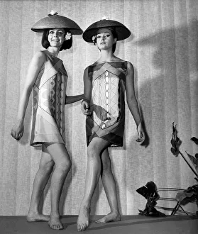 00025 Prints: Clothing Beach. Two women model patterned mini dresses and lampshade-shaped hats on stage