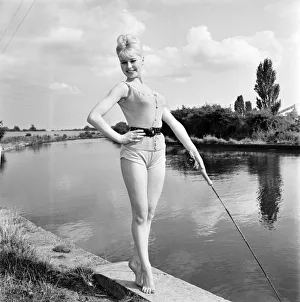 Clothing: Fashion: Beachwear: Model by the river bank fishing. August 1963 E490-009